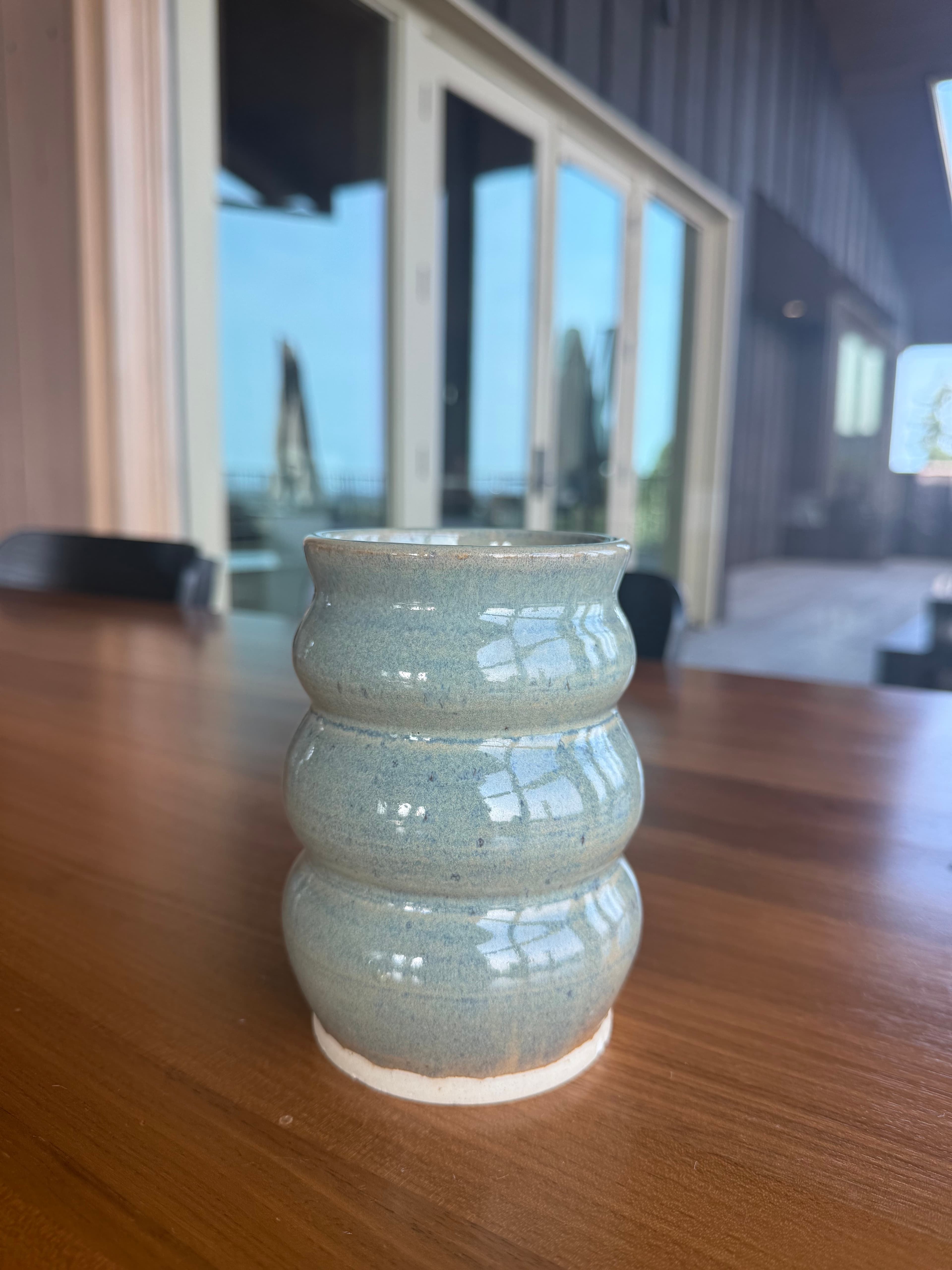 A ridged celadon vase photographed beside a window