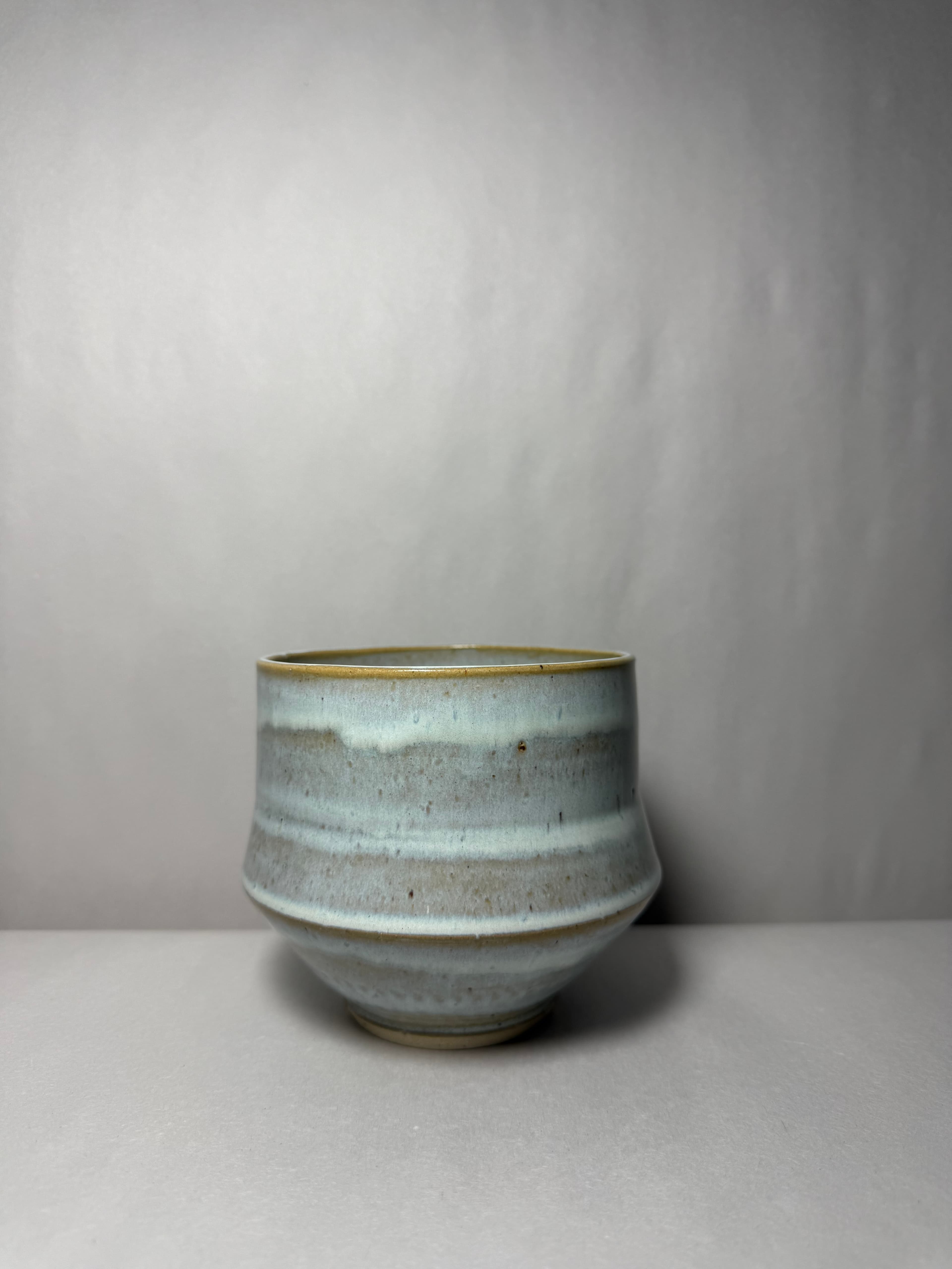 A cream striped tumbler photographed on a neutral ground