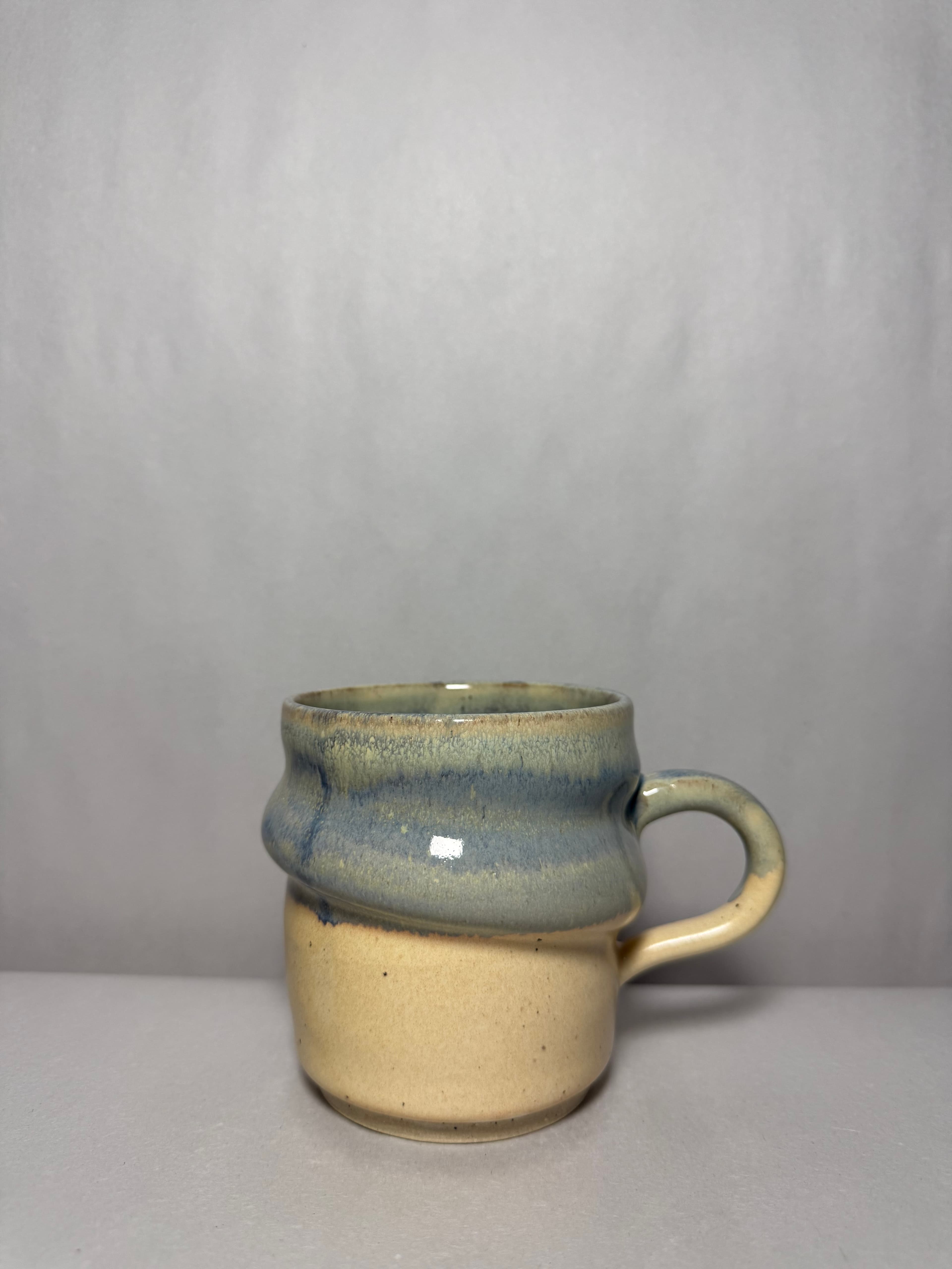 A pale blue and cream mug photographed on a neutral backdrop