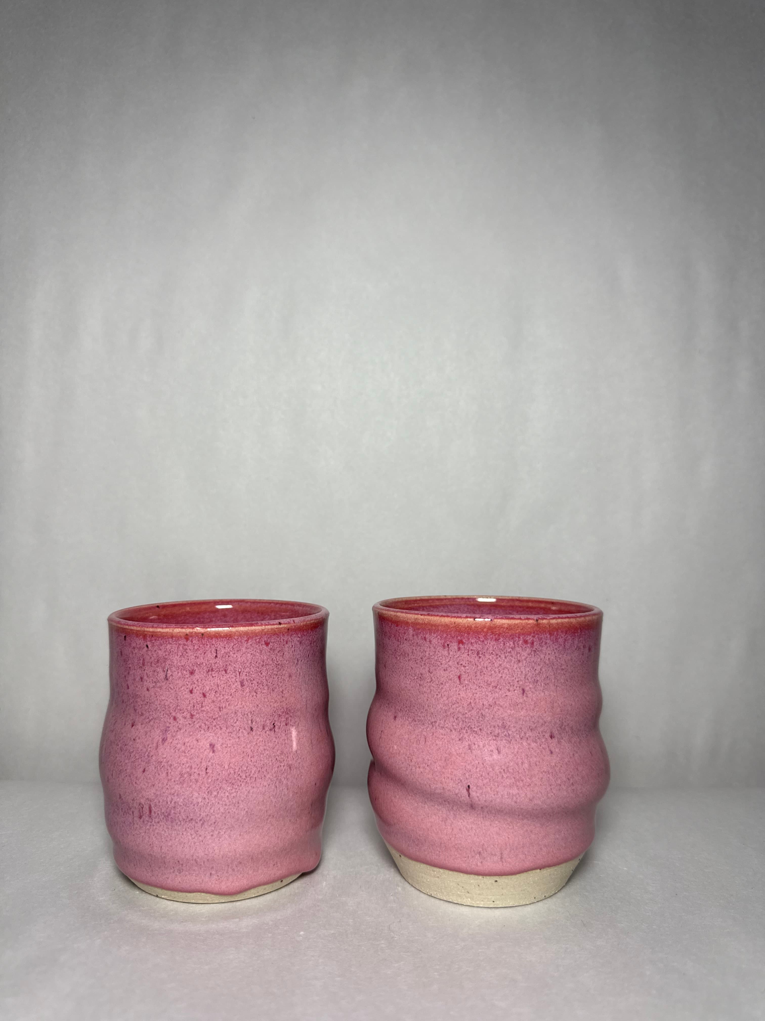 A pair of pink stoneware tumblers photographed side by side