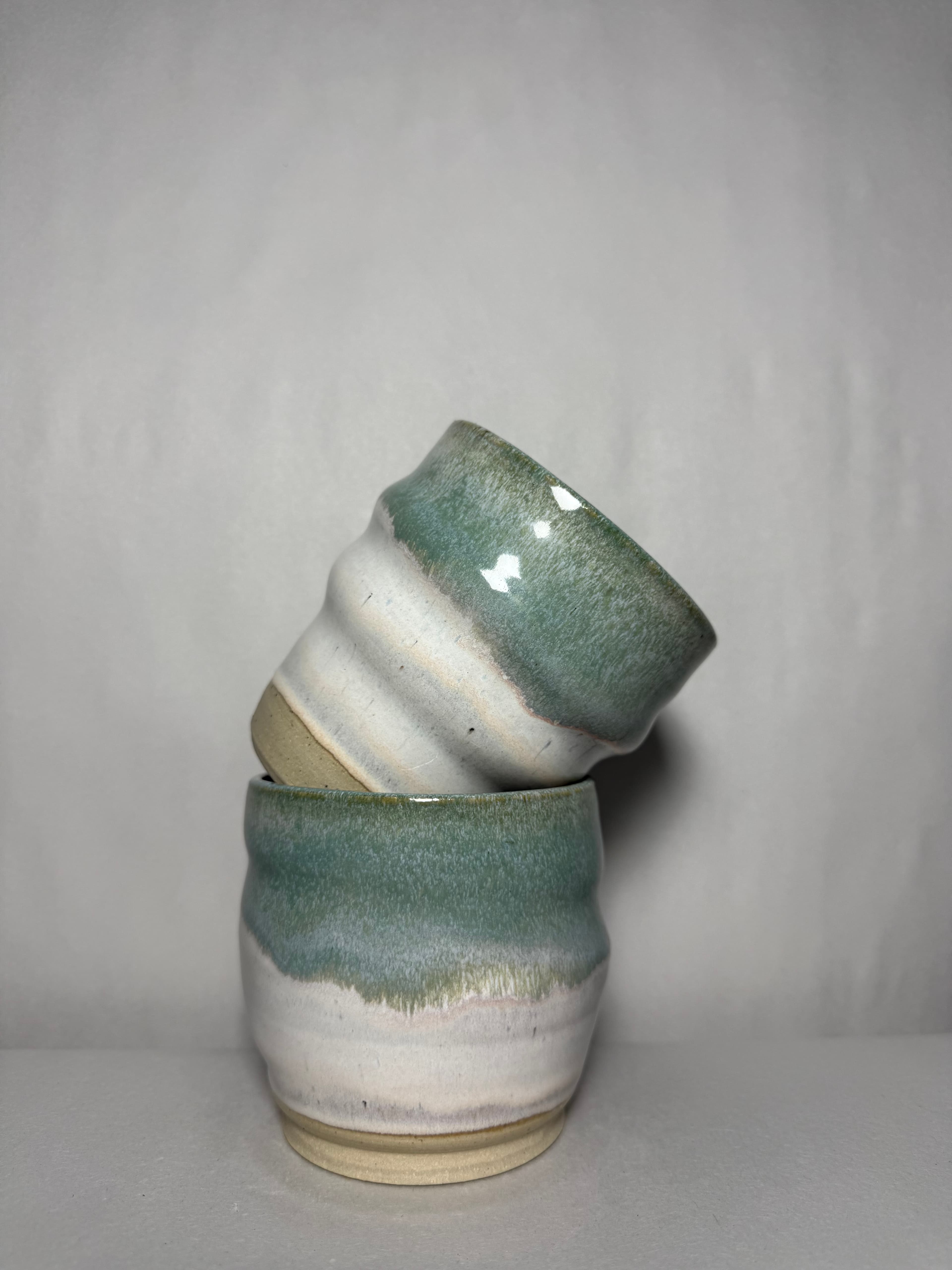 A bowl with dark drip glaze pooling over raw stoneware